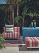 Outdoor module sofa in striped woven performance Verano Rosa with a Verano Verde cushion with greenery in the backdrop. Photography by Christopher Horwood